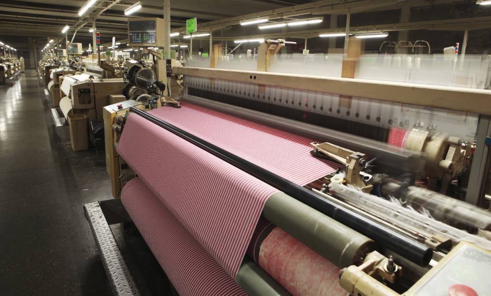 Weaving crisscross fabric on air jet looms in a textile weaving unit.